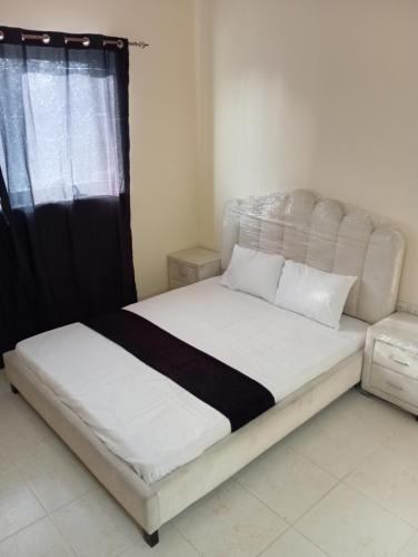 sypialnia z białym łóżkiem z czarno-białą kołdrą w obiekcie Booking to preferred room w Szardży