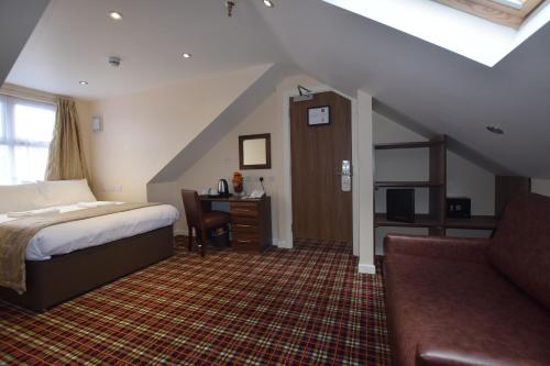 1 dormitorio con cama, escritorio y sofá en Lucky 8 Hotel, en Ilford