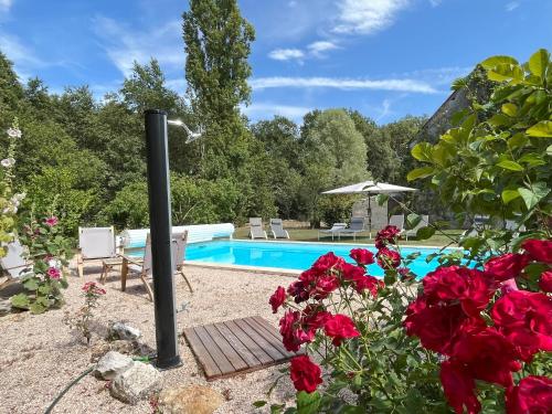 un jardin avec une piscine et des roses rouges dans l'établissement Les Gîtes de La Pellerie - 20 personnes - piscines intérieure & extérieure et Jacuzzi - 3 gîtes, à Saint-Branchs