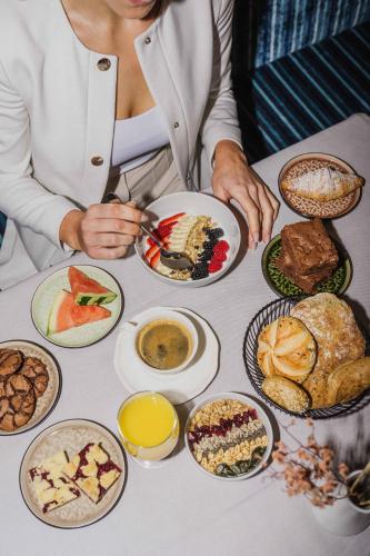 a woman sitting at a table with plates of food at Thalguter - Rooms & Breakfast in Lagundo