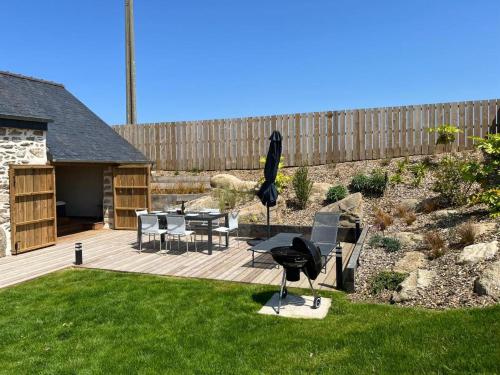 a patio with a table and chairs and an umbrella at Maison Au Bout Du Pre in Goulven
