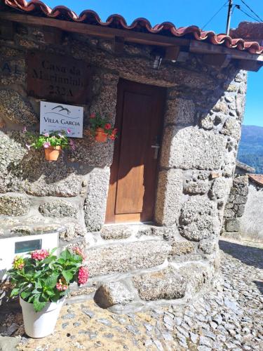 a stone building with a door and flowers in front at VillaGarcia-Casa da Marianinha in Terras de Bouro
