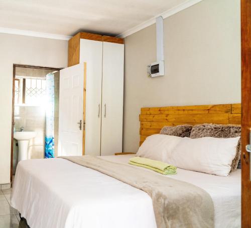 um quarto com uma cama branca e uma cabeceira em madeira em Inkanyezi Guest house em Durban
