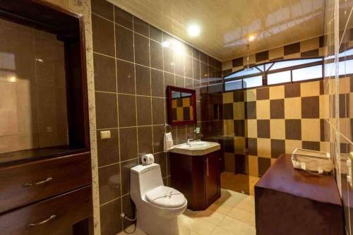 a bathroom with a toilet and a sink at Country House Arenal in San Ramón