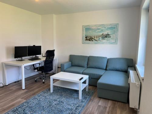 Una sala de estar con un sofá y un escritorio con una computadora. en Erholungsreich Barth, en Barth