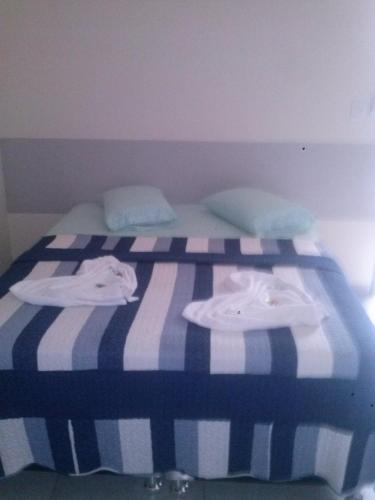 Una cama con rayas azules y blancas y toallas. en Hotel Italyan's en Ponta Porã