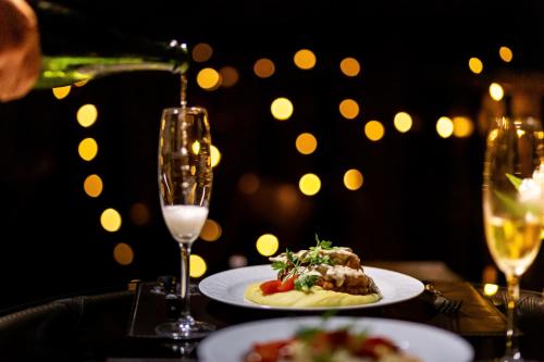 a table with two plates of food and a glass of wine at Hotel Jardins da Colina in Nova Petrópolis