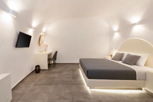 a white bedroom with a bed and a desk at Captain's house suites in Vóthon