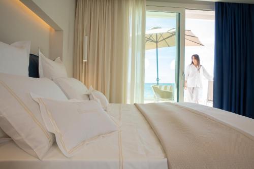 a woman standing in a hotel room with a bed at Scirocco Boutique Eco Hotel in Torre Pali 