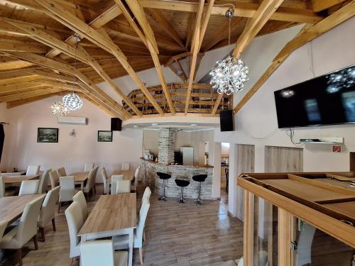 a restaurant with wooden ceilings and tables and chairs at Cserke Holdfény Apartman in Cserkeszőlő