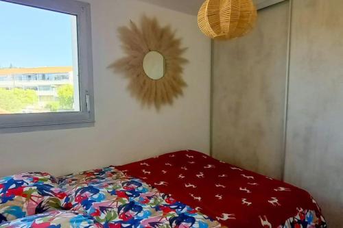- un lit avec une couverture rouge et une fenêtre dans l'établissement La Parenthèse Marine, à Bandol