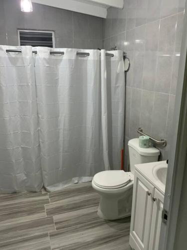 a bathroom with a white shower curtain and a toilet at Hospederia Villa Alegre Estudio 7 in Cabo Rojo