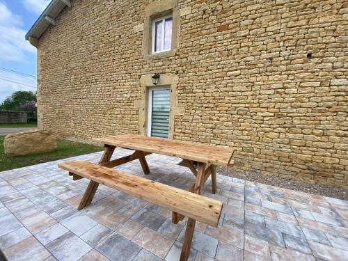 a wooden bench sitting in front of a brick building at Gîtes Marie Rose - PMR in Spincourt