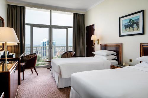 カンパラにあるSheraton Kampala Hotelのベッド2台と窓が備わるホテルルームです。