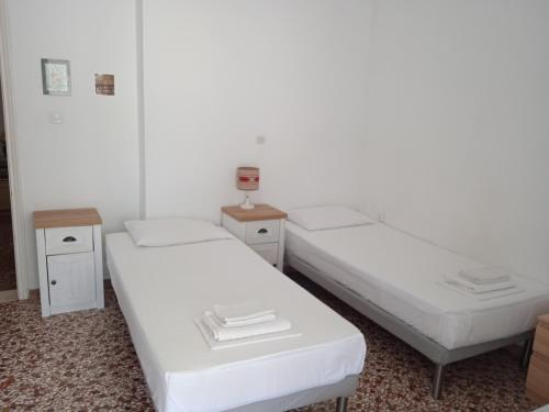 two beds in a room with white walls at Elinas Room in Poros