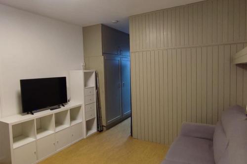 una sala de estar con TV en un centro de entretenimiento blanco en Studio 4 Personnes côté Sud, en Superdevoluy