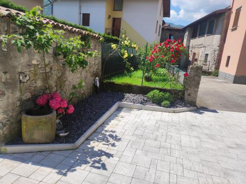 a garden with flowers next to a stone wall at Luminoso appartamento vista lago in Solto Collina