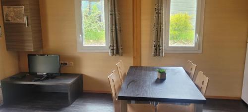 une salle à manger avec une table avec des chaises et une télévision dans l'établissement LE REFUGE de ROUSSES, à Rousses