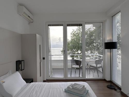 a white bedroom with a bed and a balcony at Golden Sunset Apartments in Ohrid