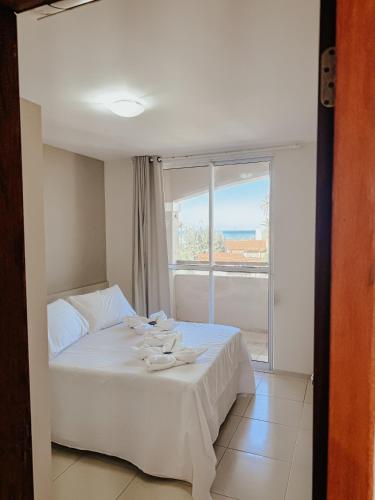 a white bed in a room with a window at Kitecabana Apartamento in Caucaia