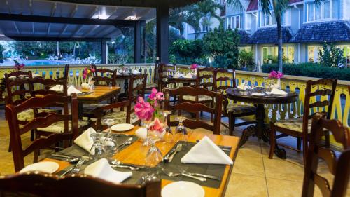 a dining room with tables and chairs with flowers on them at Coco Palm in Gros Islet
