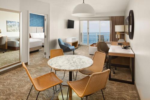 SpringHill Suites by Marriott Virginia Beach Oceanfront في فرجينيا بيتش: غرفة في الفندق مع طاولة وكراسي