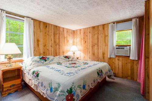 1 dormitorio con 1 cama y 2 ventanas en Hot Tub, Huge Deck, WiFi, Fire Pit at Chalet Cabin en Morton Grove