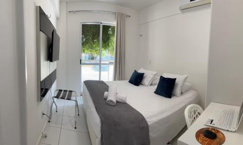 PALM BEACH Porto das Dunas, apartamento todo climatizado TÉRREO a 350 metros Beach Park في أكويراز: غرفة نوم بيضاء مع سرير كبير ومكتب
