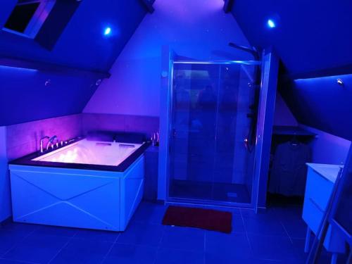 La salle de bains est pourvue d'un lavabo et d'une douche avec des lumières bleues. dans l'établissement Gîte tout confort avec baignoire balneo', à Boos