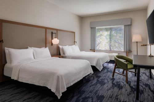 a hotel room with two beds and a desk and a window at Fairfield Inn & Suites by Marriott Kelowna in Kelowna
