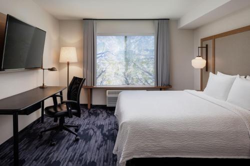 a hotel room with a bed and a desk and a window at Fairfield Inn & Suites by Marriott Kelowna in Kelowna