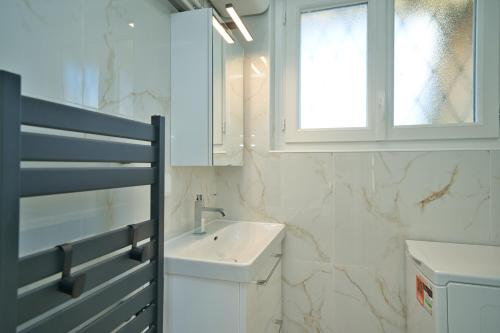 une salle de bain blanche avec un lavabo et une fenêtre dans l'établissement Studio climatisé refait à neuf, à Villeneuve-Loubet