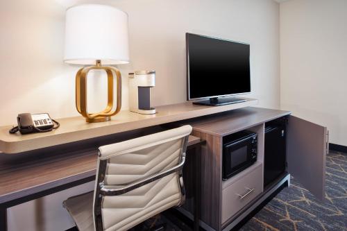 a room with a desk with a television and a chair at Holiday Inn Canton-Belden Village by IHG in Canton