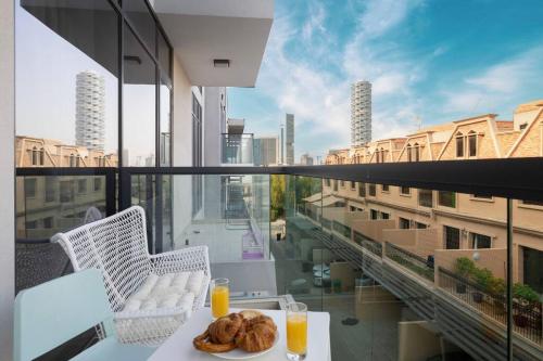 a table with a plate of bread and orange juice on a balcony at Large 1BR in JVC Sleeps 4 Rooftop, Pool & Gym in Dubai