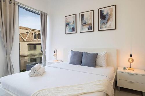 a white bedroom with two beds and a window at Large 1BR in JVC Sleeps 4 Rooftop, Pool & Gym in Dubai