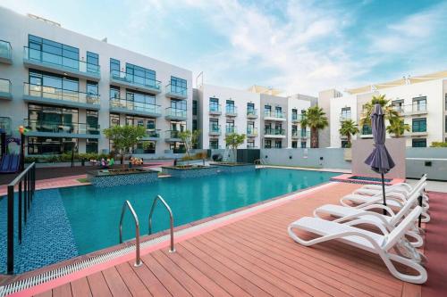 a swimming pool with lounge chairs and a building at Large 1BR in JVC Sleeps 4 Rooftop, Pool & Gym in Dubai