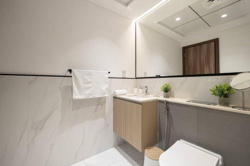 a white bathroom with a toilet and a sink at Large 1BR in JVC Sleeps 4 Rooftop, Pool & Gym in Dubai