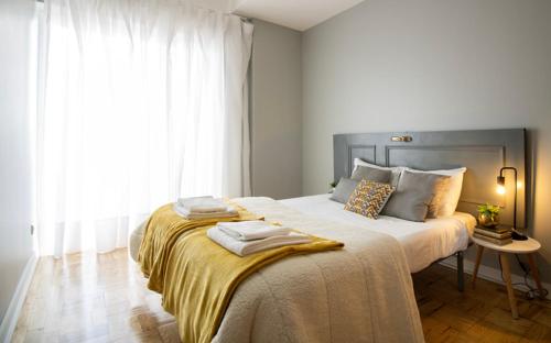 a bedroom with a large bed with two towels on it at Sunny 4 Bedroom Apartment - with View in Coimbra