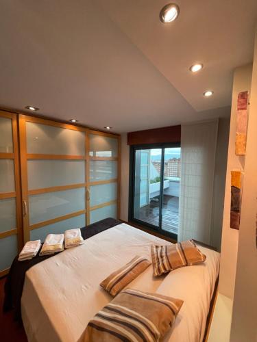 a bedroom with a large bed with a window at EL ÁTICO DE LA PLAYA Parking gratis in Gijón