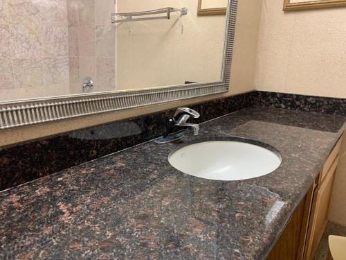 a bathroom counter with a sink and a mirror at Riverside Hotel in Casper