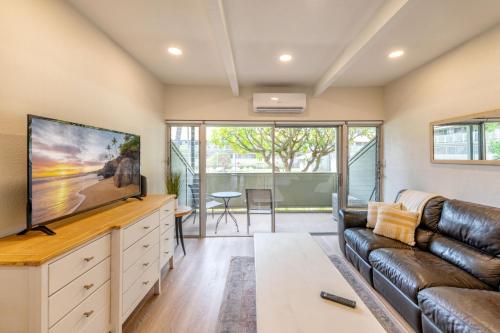 a living room with a couch and a flat screen tv at Newly Renovated Studio on First Floor in Quiet Complex Across the Street from the Beach in Kihei
