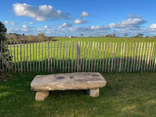 a stone bench sitting in front of a fence at Maison Au Bout Du Pre in Goulven