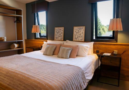 - une chambre avec un lit avec deux oreillers et deux fenêtres dans l'établissement Gluck Patagonia Aparts, à Villa La Angostura