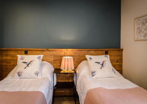 a room with two beds and a table with a lamp at Gluck Patagonia Aparts in Villa La Angostura