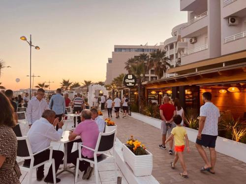 a group of people sitting at tables on a sidewalk at Gent's Inn Luxury in Durrës