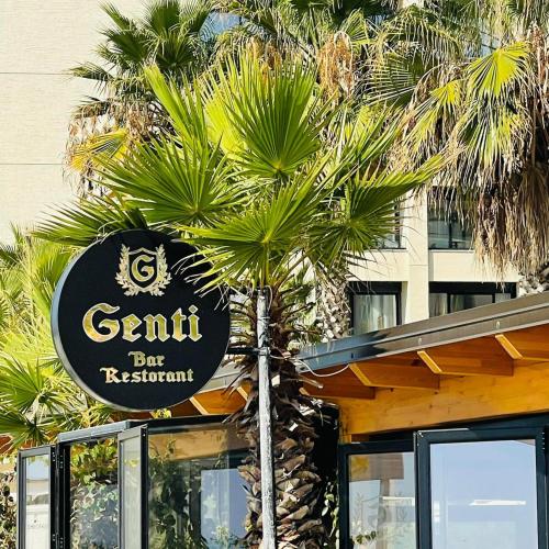 a sign for a restaurant in front of a palm tree at Gent's Inn Luxury in Durrës