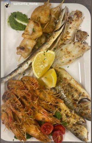 a plate of fish with lemon slices and other foods at Gent's Inn Luxury in Durrës