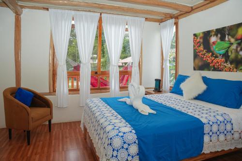 a bedroom with a bed and a chair and windows at La Casa en el Aire Mindo in Mindo