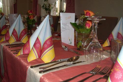 a table with a red table cloth with plates and silverware at Komforthotel-Restaurant Württemberger Hof in Bad Saulgau