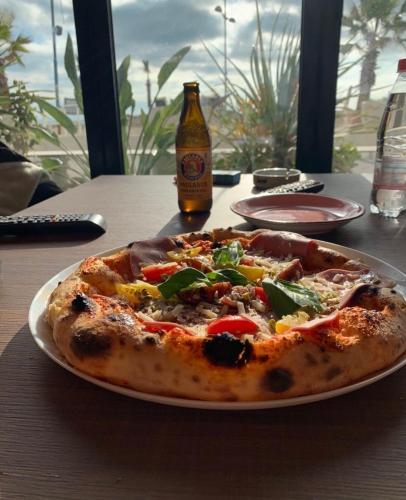 a pizza on a plate on a table with a bottle of beer at Gent's Inn Luxury in Durrës